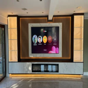 Luxury media wall Sheffield with marble-effect TV surround, backlit slatted panel, built-in electric fireplace, and illuminated display shelving by Xclusive Kitchens
