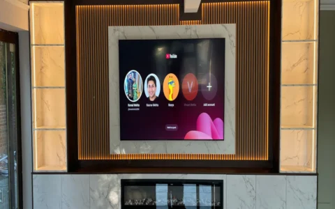 Luxury media wall Sheffield with marble-effect TV surround, backlit slatted panel, built-in electric fireplace, and illuminated display shelving by Xclusive Kitchens
