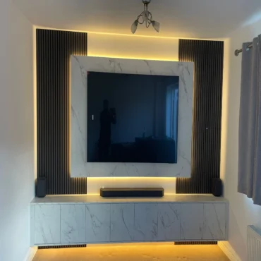 Modern luxury media wall combining marble-effect finishes, black slatted panels and ambient LED lighting for a stylish contemporary living space