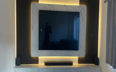 Modern luxury media wall combining marble-effect finishes, black slatted panels and ambient LED lighting for a stylish contemporary living space